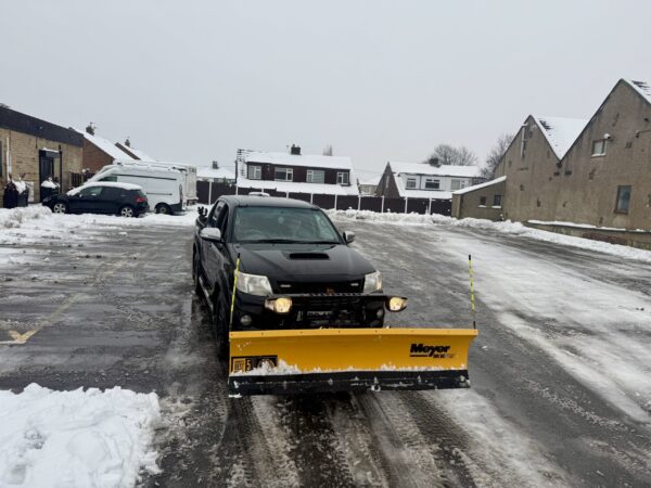 Black Hilux with Yellow Snow Plough in the Snow Carrying out Snow Clearance