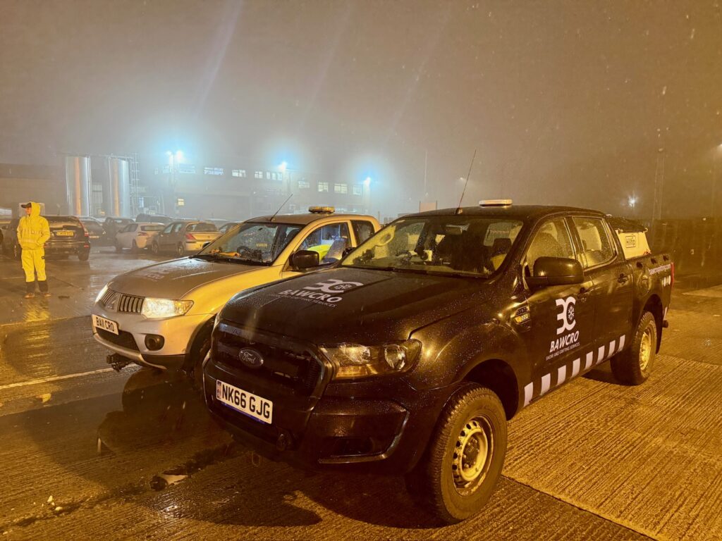 Two Bawcro Pickup Trucks Parked in an Illuminated Industrial Yard at Night